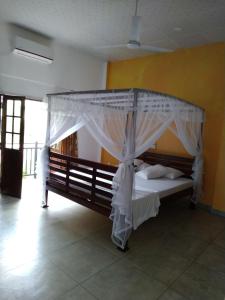 1 cama con dosel en una habitación en Kith Fiesta Villa, en Hikkaduwa