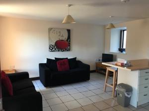 a living room with a black couch and a table at Sedbury Farm Cottages in Chepstow