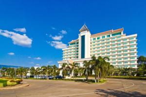 a large building with palm trees in front of a parking lot at Champasak Grand Hotel in Pakse