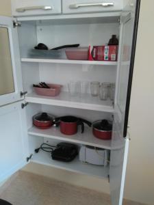 a kitchen pantry with red bowls and dishes on shelves at Casa Costa Azul - praça da Baleia in Rio das Ostras