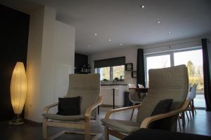 a living room with two chairs and a kitchen at Gîte du Lac in Fosses-La-Ville