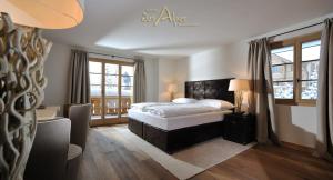 a bedroom with a bed and two windows at Hotel des Alpes Superieur in Gstaad