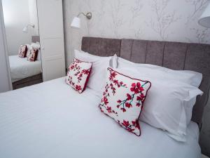 a bed with red and white pillows and a mirror at Regent Penthouse in Harrogate