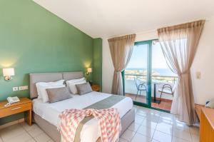 a bedroom with a large bed and a large window at Pela Mare Hotel in Agia Pelagia