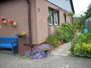 une maison en briques avec des fleurs et un banc bleu dans l'établissement Steffens, à Soltau