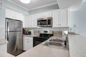 a kitchen with white cabinets and a stainless steel refrigerator at Sands Beach Club Resort in Myrtle Beach