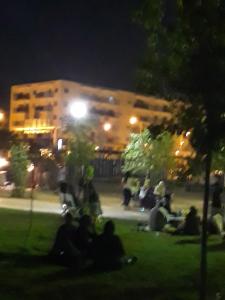 people sitting in the grass in front of a building at night at Appartement Akid Lotfi Oran in Oran