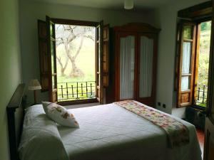 a bedroom with a large bed with a window at Finca Artienza in Ramales de la Victoria