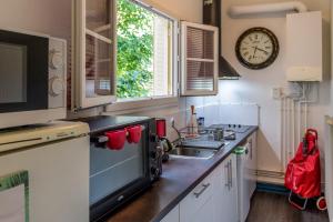 una cocina con fregadero y un reloj en la pared en La ptite chouette en Dijon