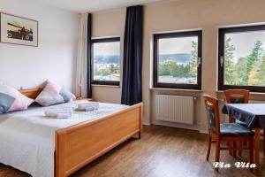Schlafzimmer mit einem Bett, einem Tisch und Fenstern in der Unterkunft Gasthof Via Vita in Treuchtlingen