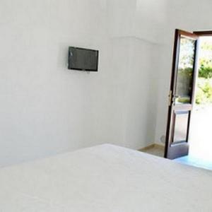 um quarto com uma cama branca e uma televisão na parede em Masseria Lama D'impisa em Fasano