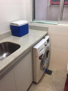 uma cozinha com um lavatório e uma máquina de lavar roupa em Apto 2suítes 30m da praia em Florianópolis