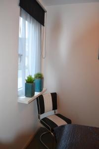 a bedroom with a chair and a window with plants at Bed & Breakfast ‘t Westergouwertje in Gouda