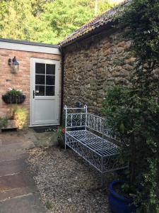 a bench in front of a stone building with a door at The coach house in Grimston