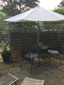 stół i dwa krzesła pod parasolem w obiekcie The coach house w mieście Grimston