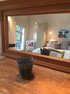 um espelho num quarto com uma cama e uma cadeira em The coach house em Grimston