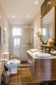 a bathroom with a toilet and a sink and a mirror at Pela Mare Hotel in Agia Pelagia