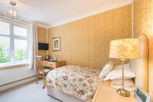 a bedroom with a bed and a desk with a lamp at Grovefield Manor in Poole