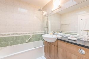 a bathroom with a sink and a tub at Grovefield Manor in Poole