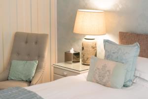 a bedroom with a bed with a chair and a lamp at Grovefield Manor in Poole