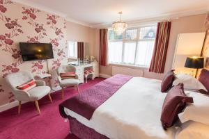 a bedroom with a large bed and a desk and chairs at Grovefield Manor in Poole