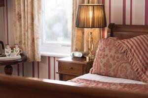 a bedroom with a bed with a lamp and a window at Grovefield Manor in Poole