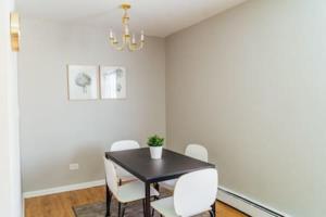 1BR Stylish Apartment, Perfect for Getaway - Oakdale 201 في شيكاغو: غرفة طعام مع طاولة سوداء وكراسي بيضاء