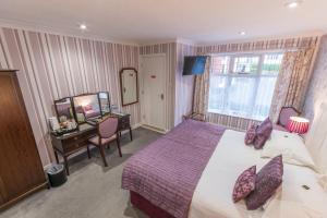 a bedroom with a bed and a desk and a mirror at Grovefield Manor in Poole