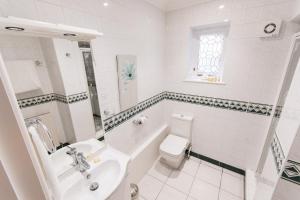 a white bathroom with a toilet and a sink at Grovefield Manor in Poole