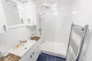 a white bathroom with a shower and a sink at Grovefield Manor in Poole