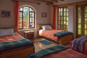 1 dormitorio con 2 camas y 2 ventanas en INTIYAYA - Residence, en Otavalo