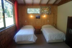Habitación pequeña con 2 camas y 2 ventanas en Ecoreserva Quelhue Lodge y Cabañas, en Pucón
