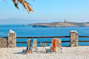 two chairs and a table in front of the ocean at Aegean View - Seaside Apartment in Syros in Azolimnos