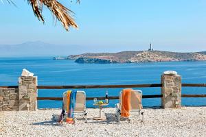 two chairs and a table in front of the ocean at Aegean View - Seaside Apartment in Syros in Azolimnos Syros