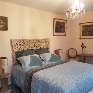 a bedroom with a bed and a chandelier at La table de Pierre in Lussas-et-Nontronneau