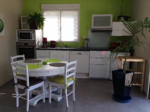 eine Küche mit einem weißen Tisch und Stühlen in einem Zimmer in der Unterkunft Les Écorchoux c'est chou in Tossiat