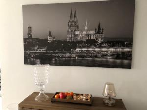 a table with a bowl of fruit and a picture of a city at Rheinblick Sommershof in Cologne