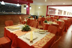 een eetkamer met tafels en stoelen met rode tafellakens bij HOSTAL EL POLIGONO in La Roda