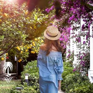 una mujer con un sombrero de paja caminando por un jardín en Blue & White Hotel, en Cıralı