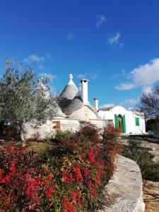 a white house with red flowers in front of it at Il Trullo del Nonno a Cisternino in Cisternino