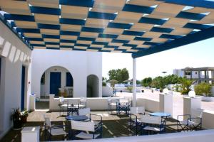 a patio with chairs and tables under a blue ceiling at Blue Bay Villas in Kamari