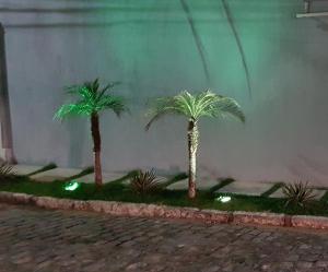 three palm trees in front of a building with lights at Apartamento Cabo Frio in Cabo Frio
