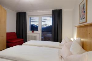 um quarto com uma cama, uma cadeira vermelha e uma janela em Ferienwohnungen Tiroler Alpenhof em Innsbruck