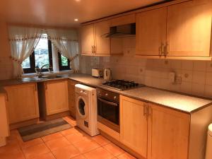 cocina con armarios de madera, lavadora y secadora en The Cottage, cosy 2 bedroom pet friendly perfect for contractors free secure parking,CCTV en Leeds