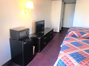 a hotel room with a television and a bed at American Inn & Suites in Albuquerque