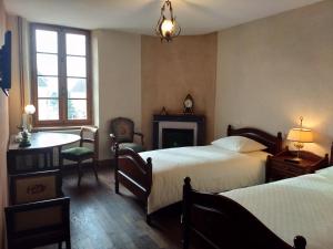 1 dormitorio con 2 camas, mesa y chimenea en Chez Casimir, en Cercy-la-Tour