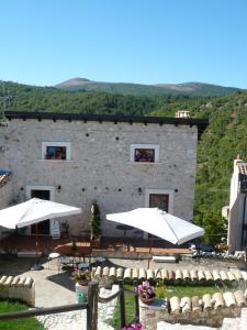 Caporciano的住宿－Regio Tratturo，前面有桌子和伞的建筑