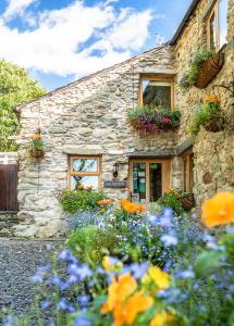 a stone house with flowers in front of it at The Wayside and Whisky Barn in Whitbeck