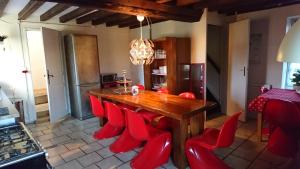 une cuisine avec une table en bois et des chaises rouges dans l'établissement Tricolore Normandie, à MÃ©nil-Vin