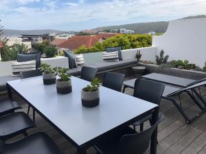 a patio with tables and chairs on a roof at 7 The Dunes, Sanctuary Beach in Plettenberg Bay